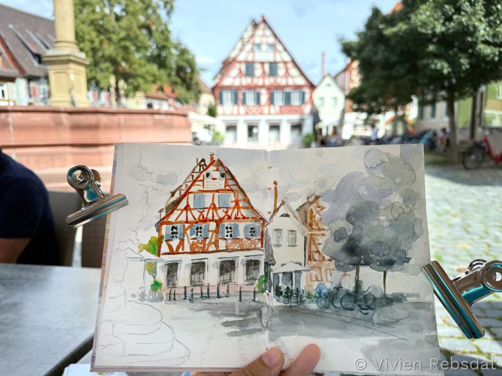 Sketchbook Seite mit Aquarell von einem Fachwerkaus am Marktplatz Ladenburg, das Haus ist im Hintergrund zu sehen